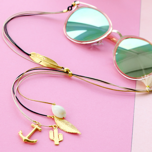 Zomerse zonnebrilkoorden met gouden details en minimalistische oorbellen van stainless steel.